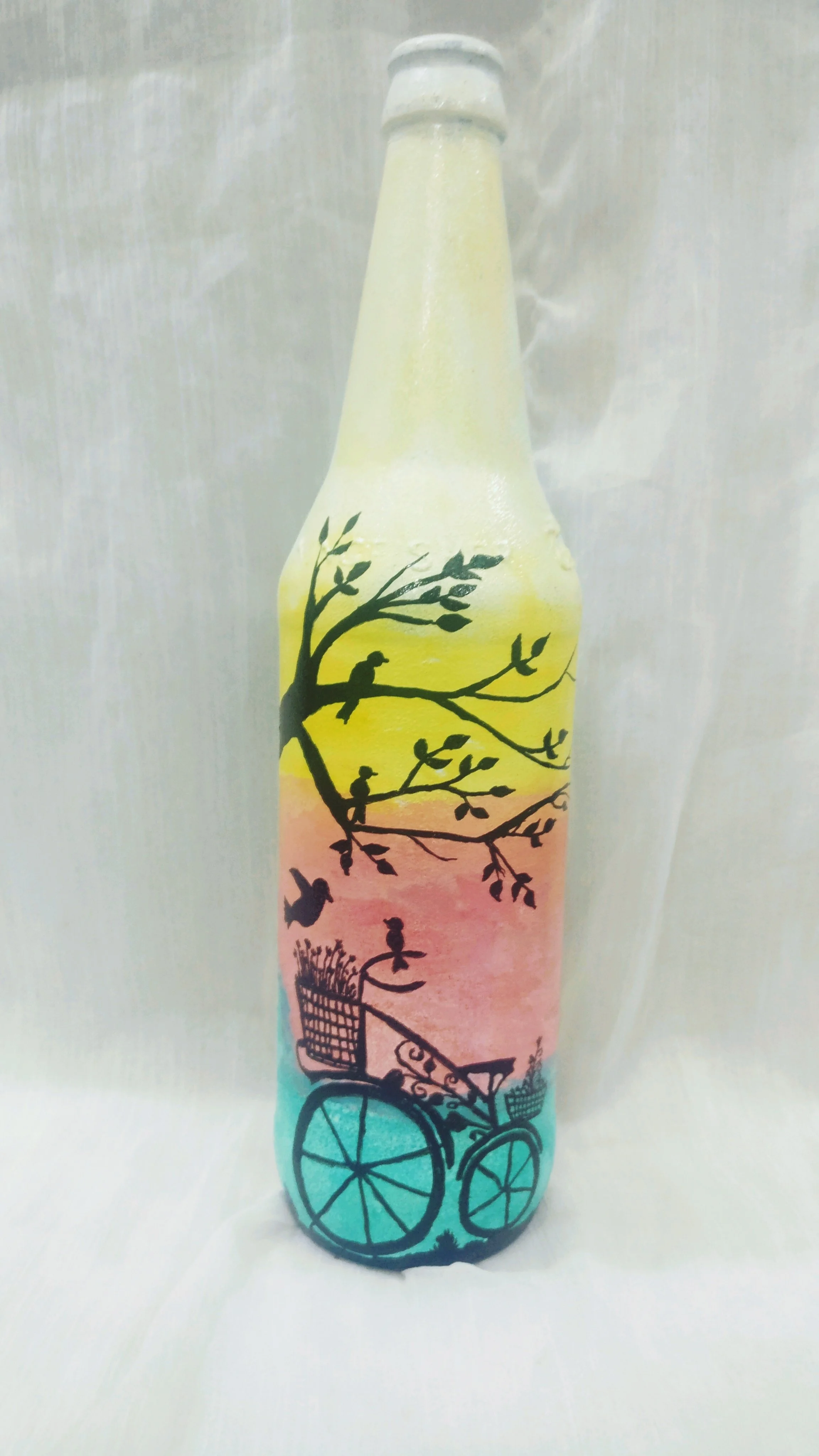 Chai thủy tinh màu pastel vẽ cành cây và xe đạp bên dưới