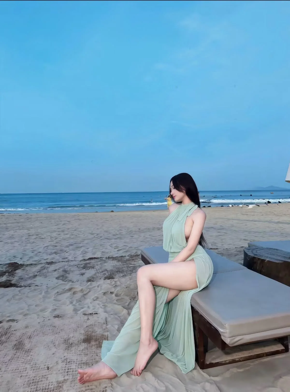 Gái xinh che mặt ngồi trên ghế dài ngắm biển