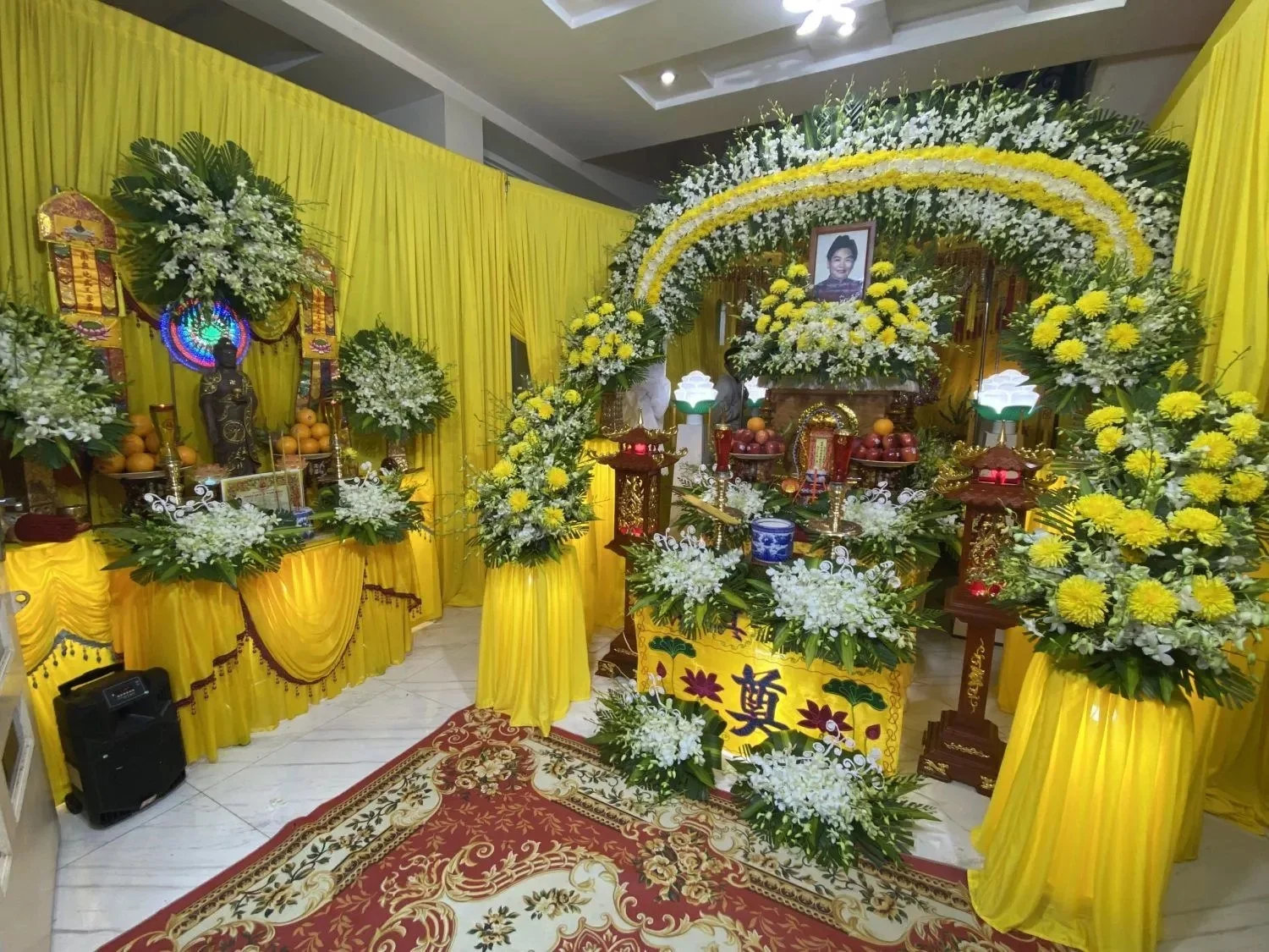 Cách trang trí bàn thờ trong ảnh đám tang với tông màu vàng và hoa tươi trang trọng